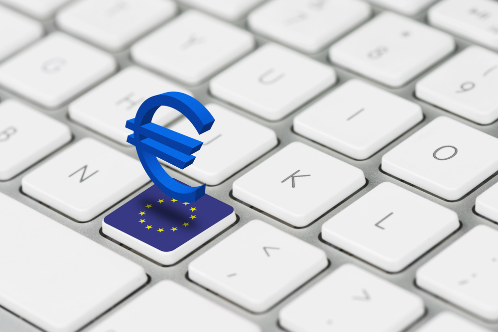 Klawiatura laptopa. Na jednym klawiszu flaga Unii Europejskiej. Nad tym klawiszem zawieszony niebieski symbol waluty euro.
