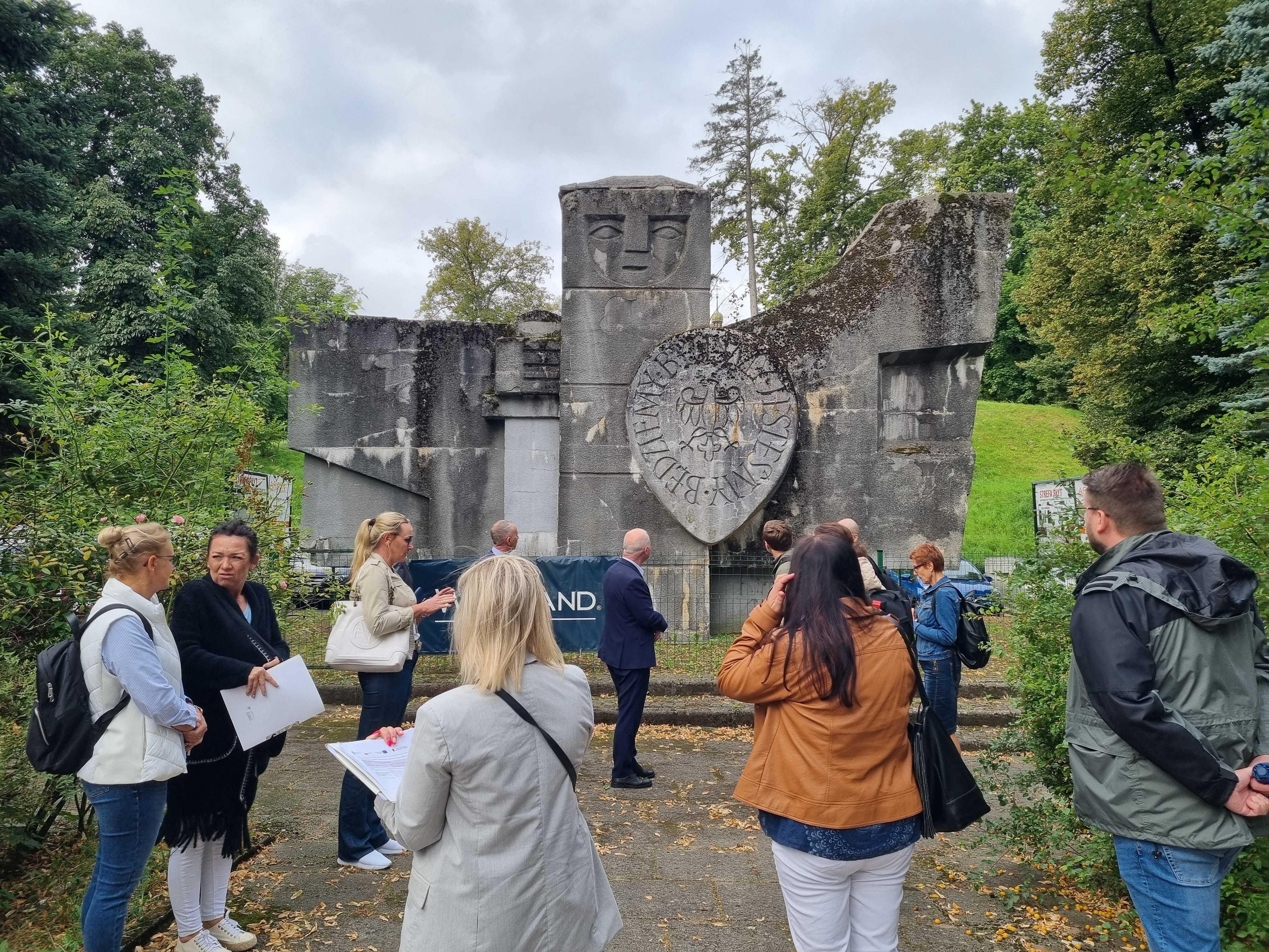 Grupa ludzi stojąca pod pomnikiem