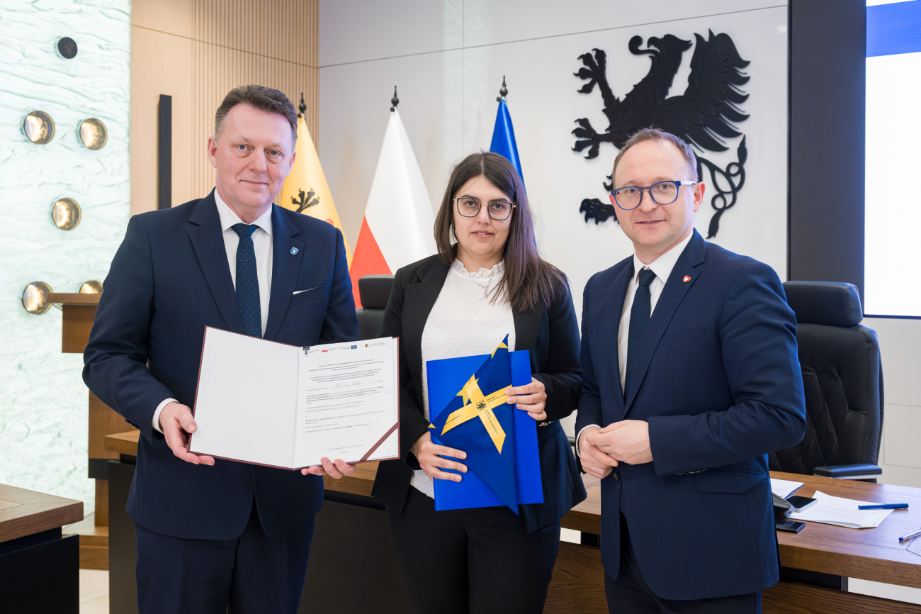 Trzy osoby prezentują podpisaną umowę