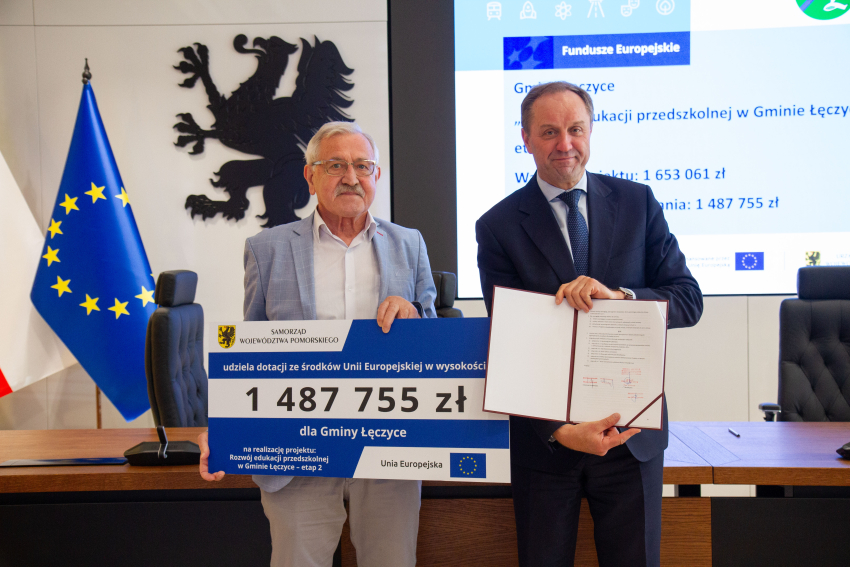 Marszałek Mieczysław Struk i przedstawiciel gminy trzymają czek informujący o dofinansowaniu