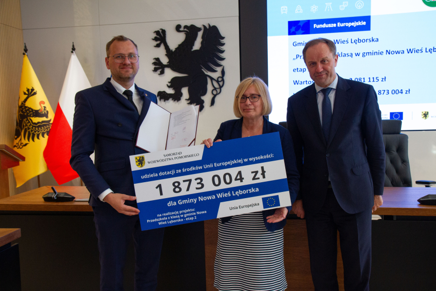 Marszałek Mieczysław Struk i przedstawiciele gminy trzymają czek informujący o dofinansowaniu