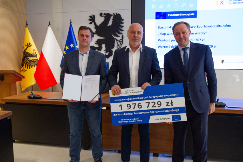 Marszałek Mieczysław Struk i przedstawiciele gminy trzymają czek informujący o dofinansowaniu