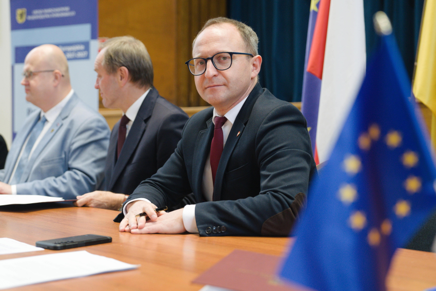 Wicemarszałek Marcin Skwierawski i dwie inne osoby siedzą przy stole prezydialnym