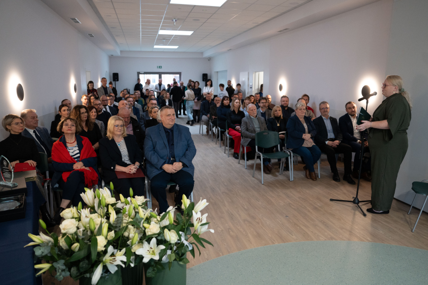 Grupa ludzi w sali siedzi na krzesłach