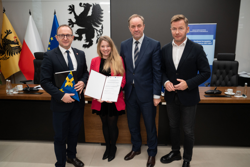 Marszałek Mieczysław Struk, wicemarszałek Marcin Skwierawski i dwoje przedstawicieli władz lokalnych prezentują podpisaną umowę i flagę Unii Europejskiej.