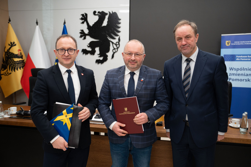 Marszałek Mieczysław Struk, wicemarszałek Marcin Skwierawski i jeden z przedstawicieli władz lokalnych prezentują podpisaną umowę i flagę Unii Europejskiej.