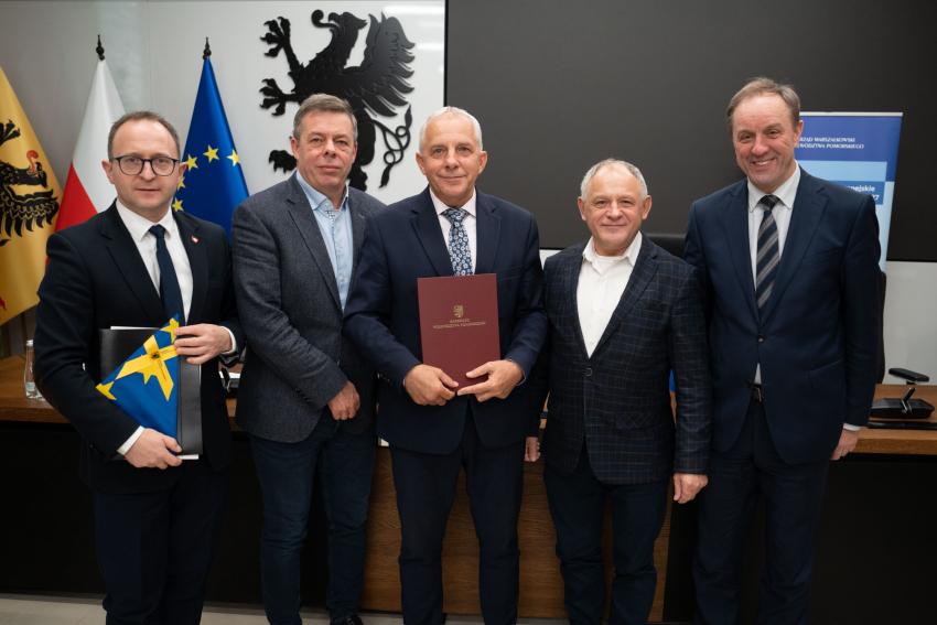 Marszałek Mieczysław Struk, wicemarszałek Marcin Skwierawski i trzech przedstawicieli władz lokalnych prezentują podpisaną umowę i flagę Unii Europejskiej.