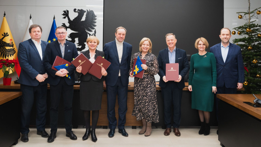 Zdjęcie zbiorowe ośmiu osób prezentujących podpisane umowy. Wśród nich marszałek Mieczysław Struk.