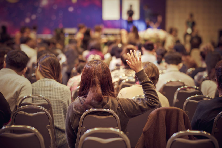 Widok sali konferencyjnej. Kobieta podnosi rękę
