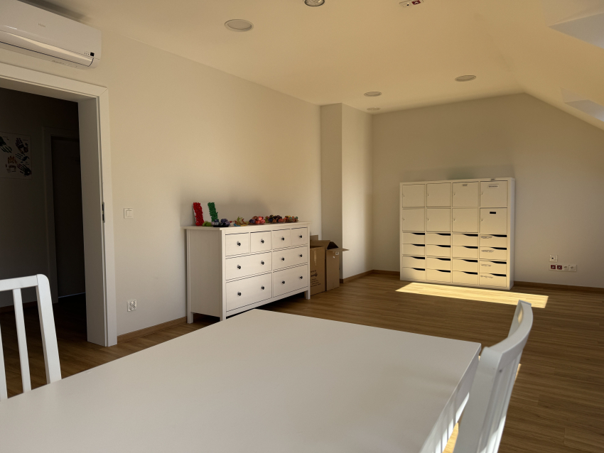 Pokój dla osoby z autyzmem w budynku. W ujęciu stół z krzesłami, szafka i komoda