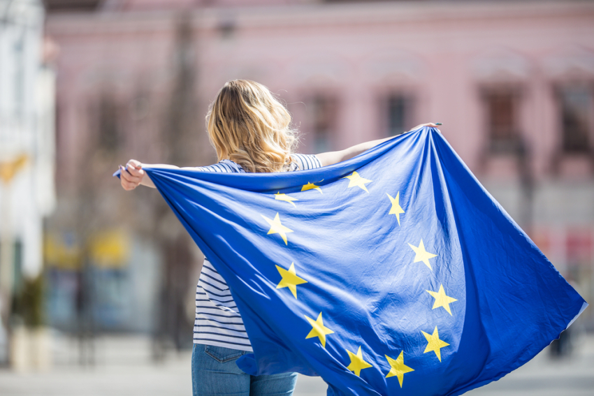 grafika przedstawia kobietę z flagą Unii Europejskiej