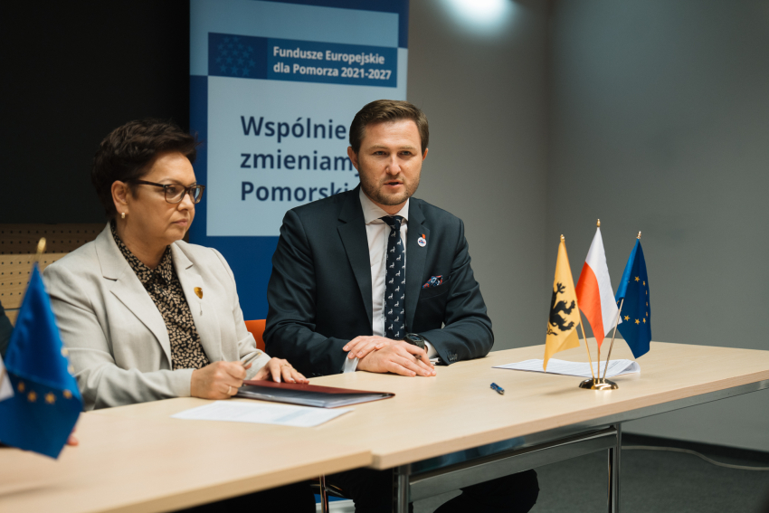 Zdjęcie: Łukasz Tokarczyk/Pomorskie.eu Zdjęcie przestawia dwie osoby siedzące przy stole prezydialnym.