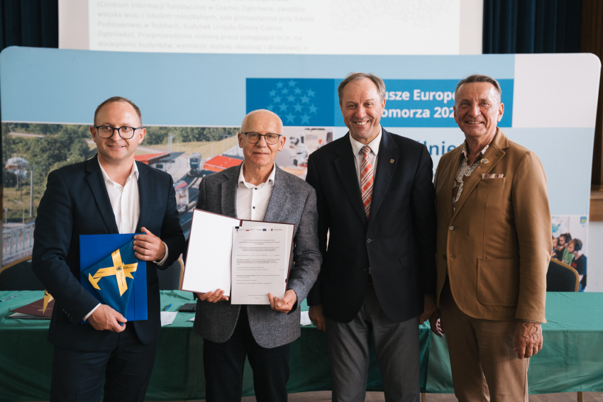 Marszałek Mieczysław Struk, wicemarszałek Marcin Skwierawski i wicemarszałek Leszek Bonna wraz z przedstawicielem jednej z gmin prezentują podpisaną umowę oraz flagę Unii Europejskiej.