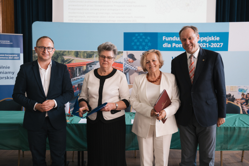 Marszałek Mieczysław Struk, wicemarszałek Marcin Skwierawski oraz dwie przedstawicielki Stowarzyszenia Przyjaciół Szkół Katolickich w Gminie Gniew prezentują podpisaną umowę oraz flagę Unii Europejskiej.