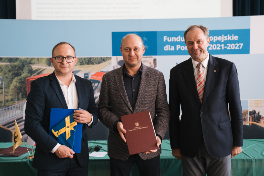 Marszałek Mieczysław Struk, wicemarszałek Marcin Skwierawski oraz przedstawiciel jednej z gmin prezentują podpisaną umowę oraz flagę Unii Europejskiej.