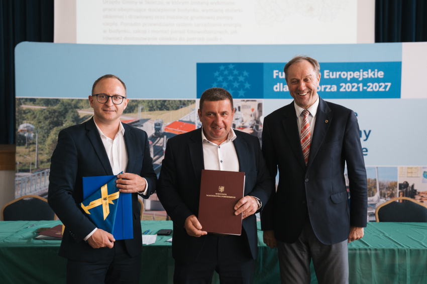 Marszałek Mieczysław Struk, wicemarszałek Marcin Skwierawski oraz przedstawiciel jednej z gmin prezentują podpisaną umowę oraz flagę Unii Europejskiej.