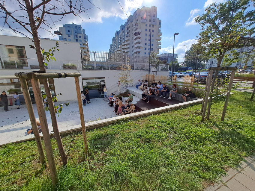 Nowoczesny budynek z pasem zieleni, bloki mieszkalne w tle