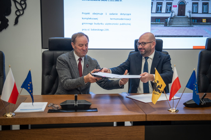 Dwie osoby przekazują sobie umowę do podpisu 