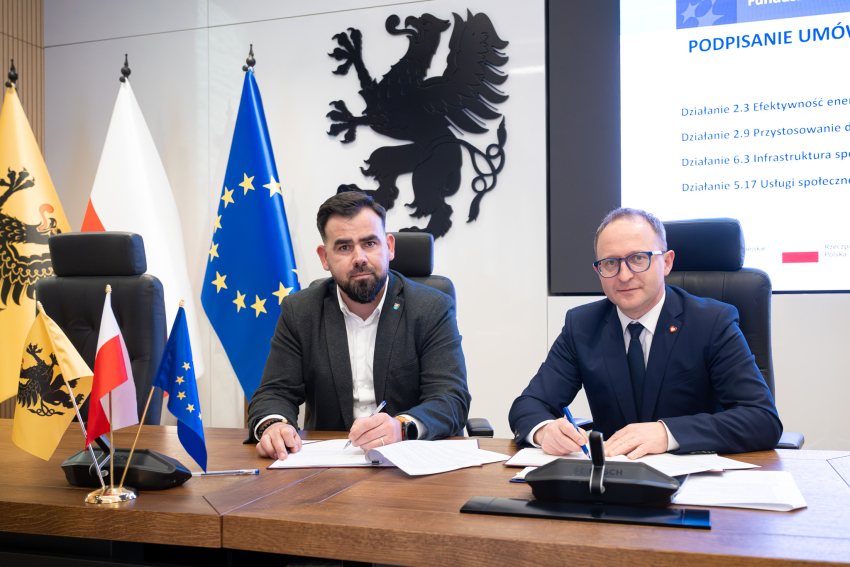 Dwie osoby siedzą za stołem i podpisują umowę. Po lewej Starosta Powiatu Lęborskiego - Pan Tomasz Litwin, po prawej - wicemarszałek województwa pomorskiego - Marcin K. Skwierawski. 