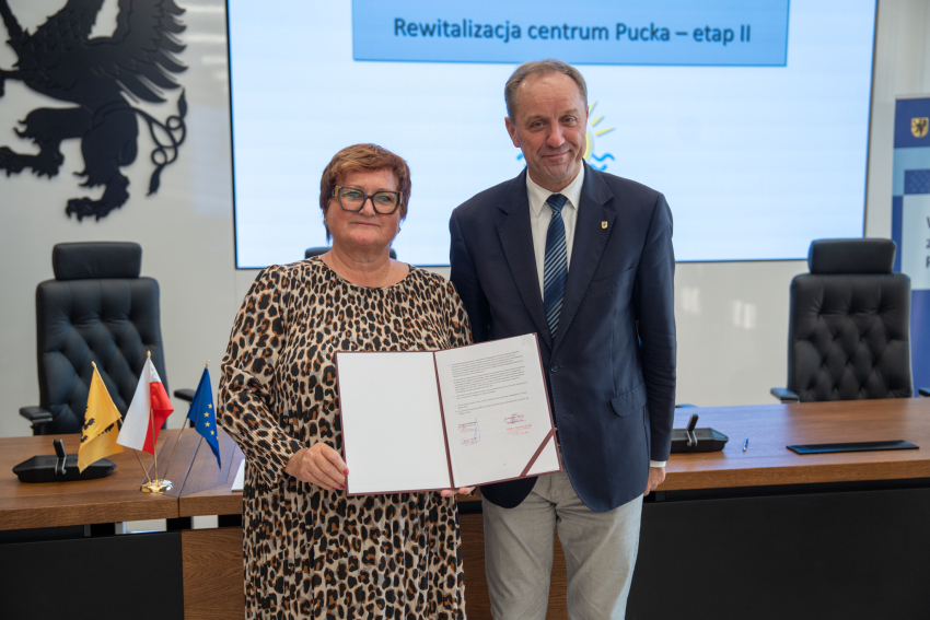 marszałek Mieczysław Struk oraz przedstawicielka lokalnych władz pozują do zdjęcia prezentując podpisane porozumienie