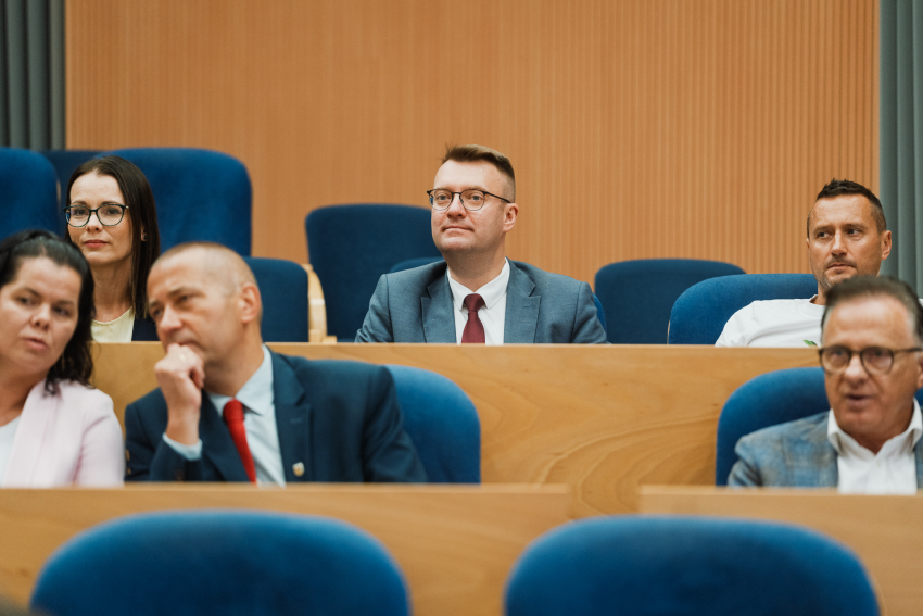 kilka osób siedzi i przysłuchuje się