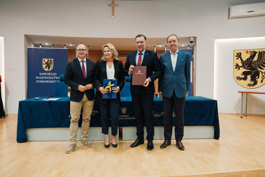marszałkowie oraz dwóch przedstawicieli lokalnych władz pozują do zdjęcia z umową i flagą UE