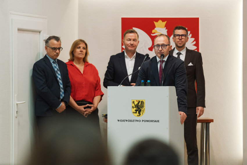 Senator Ryszard Świlski przemawia do zebranych z mównicy. Przy nim stoi pięć osób, wśród nich pracownicy UMWP