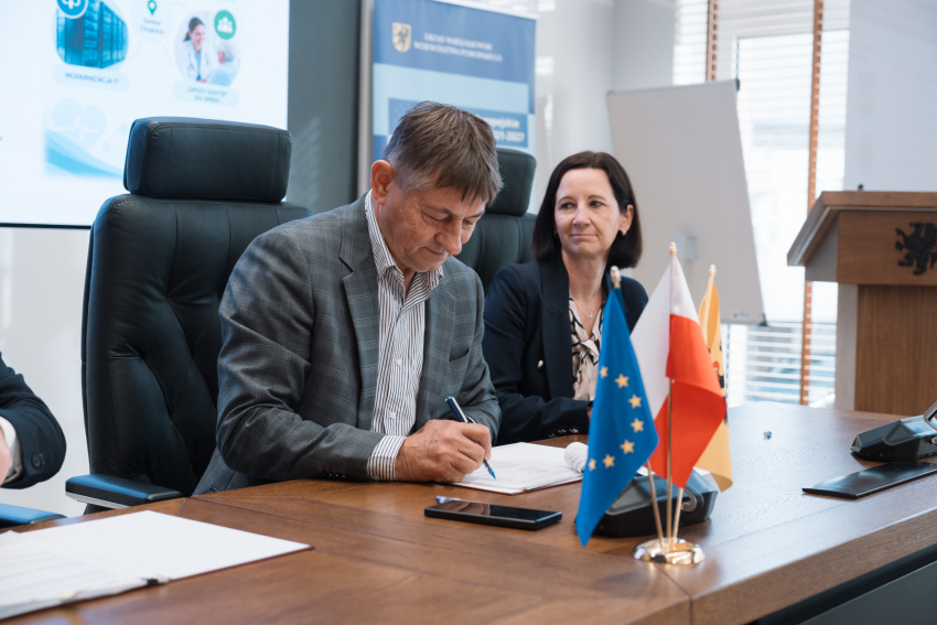 Wójt Chojnic Zbigniew Szczepański podpisuje przy stole prezydialnym umowę o dofinansowanie