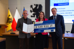 Marszałek i przedstawilciele gminy trzmaja czek informujący o dofinansowaniu