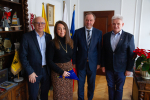 Cztery osoby w gabinecie. Kobieta trzyma flagę. W środku Marszałek Mieczysław Struk