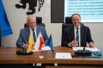 marszałek Mieczysław Struk oraz przedstawiciel lokalnych władz podpisują porozumienie przy stole prezydialnym