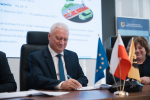 Przedstawiciel lokalnych władz podpisuje przy stole prezydialnym umowę o dofinansowanie