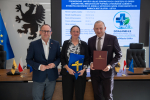 Wicemarszałek Marcin Skwierawski oraz dwóch przedstawicieli lokalnych władz pozują do uroczystego zdjęcia prezentując podpisaną umowę o dofinansowanie oraz flagę UE