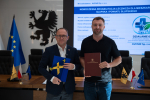 Wicemarszałek Marcin Skwierawski oraz przedstawiciel AVENIR Sp. z o.o. pozują do uroczystego zdjęcia prezentując podpisaną umowę o dofinansowanie oraz flagę UE