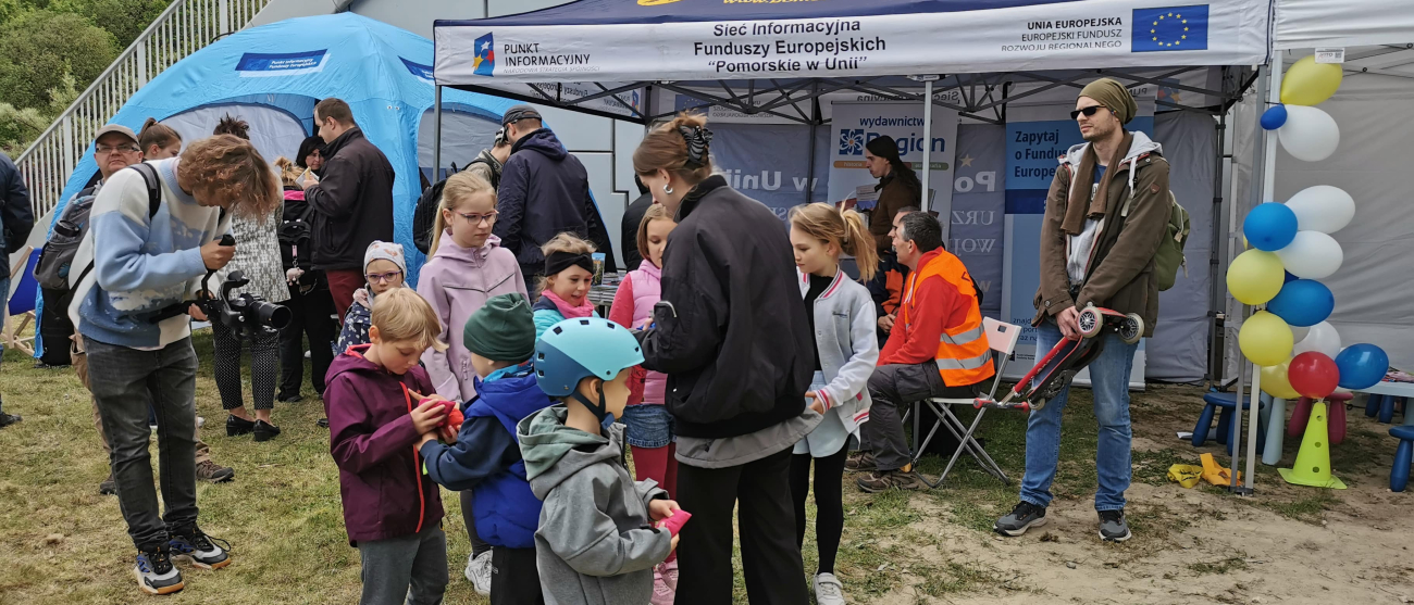 dzieci na tle na namiotu Sieci Punktów Informacyjnych Funduszy Europejskich