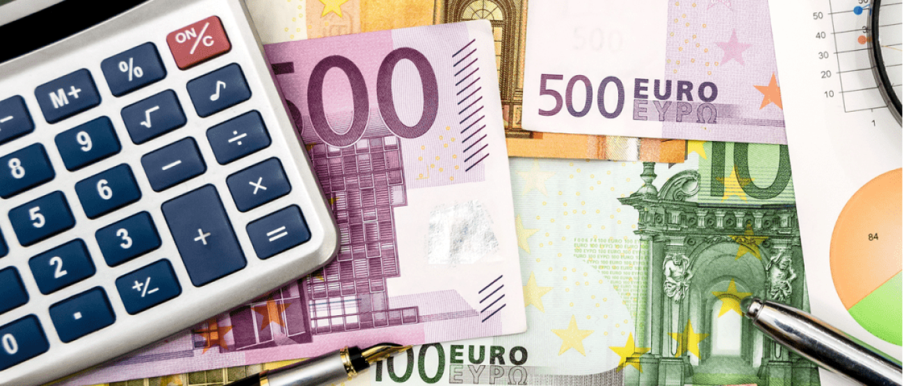 Na stole leżą rozłożone banknoty euro. Na kilku banknotach leży kalkulator i eleganckjie  