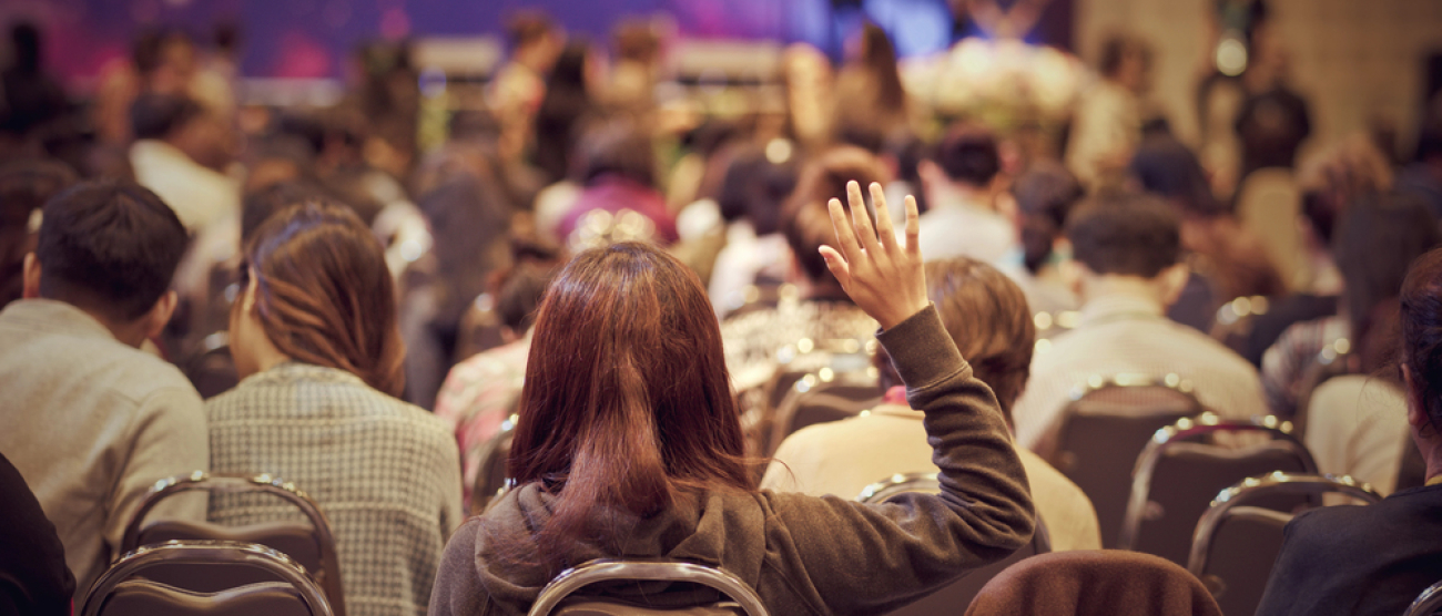 Widok sali konferencyjnej. Kobieta podnosi rękę