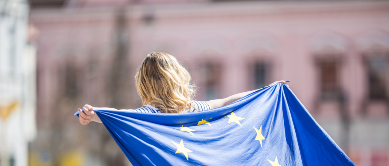 grafika przedstawia kobietę z flagą Unii Europejskiej