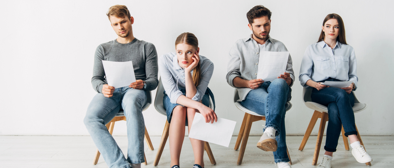 Dwie kobiety i dwóch mężczyzn. Siedzą na krzesłach maja w rękach kartki. 