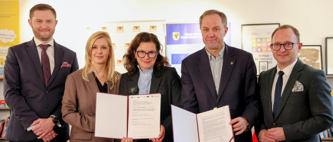 Pięć osób pozujących do zdjęcia w garniturach trzymając foldery z dokumentami