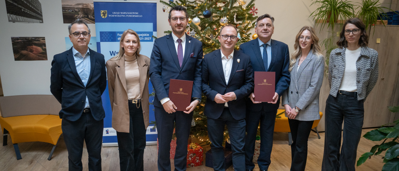 Elegancko ubrani ludzie z dokumentami, w tle choinka