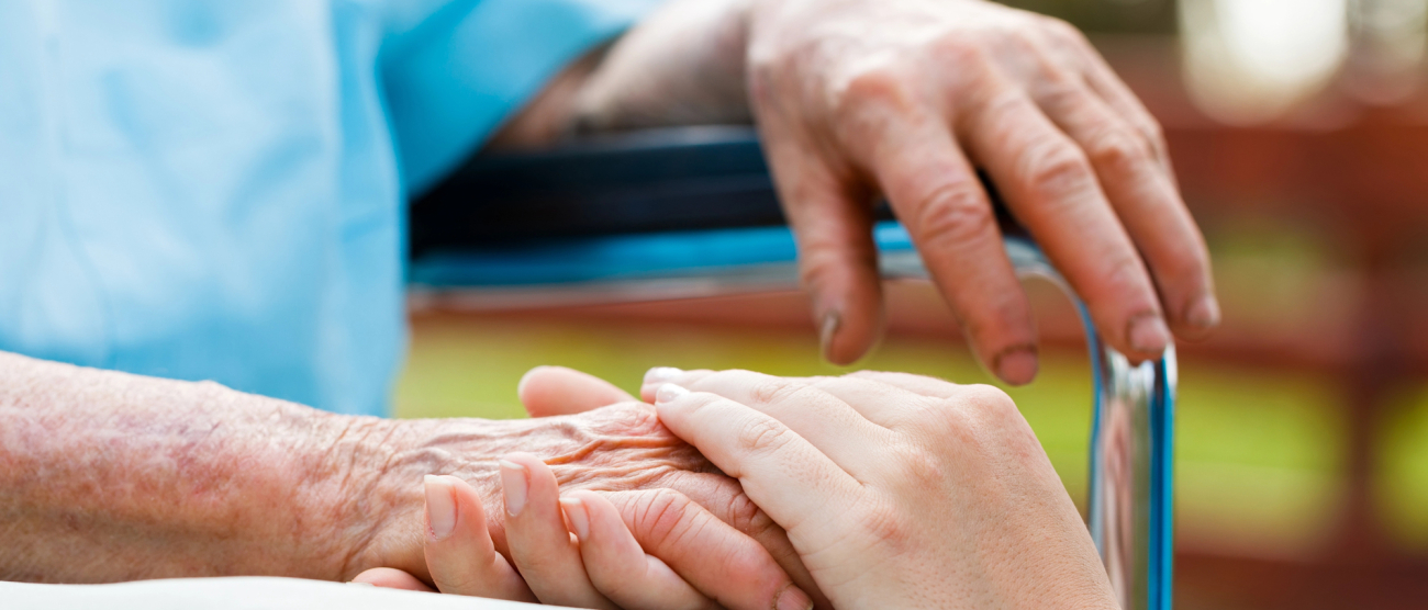 Dłoń starszej osoby obejmowana przez inna dłoń 