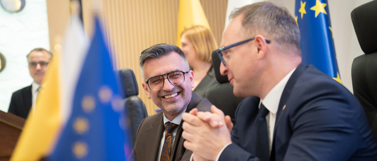 Od lewej: Burmistrz Czerska Burmistrz Czerska - Daniel Szpręga oraz wicemarszałek województwa pomorskiego Marcin Skwierawski uśmiechają się i rozmawiają przy stole prezydialnym